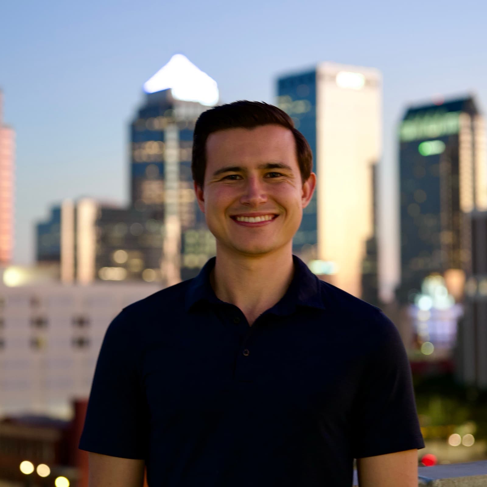 Austin Hunt on a rooftop at dusk with the downtown Tampa skyline behind him