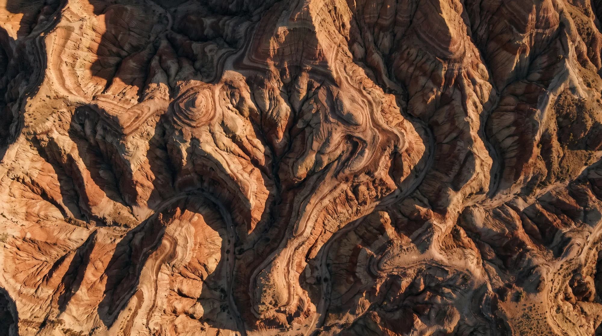 Aerial view of eroded badlands where natural drainage forms contour-like ridges